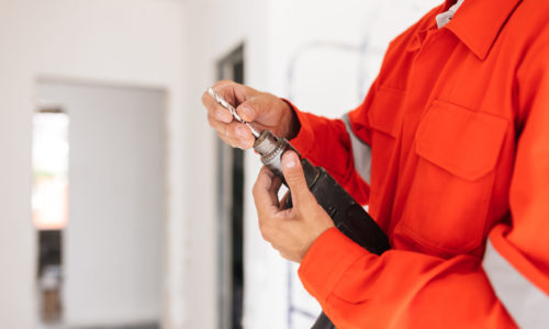 München 3 close up builder in orange work clothes holding 53ZM4DW scaled